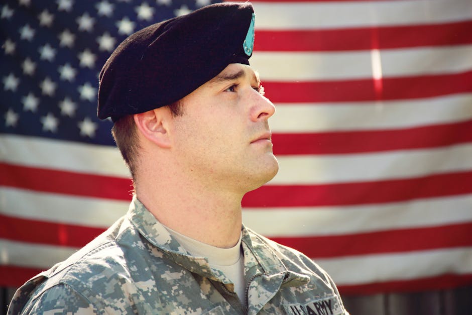 US soldier in uniform stands proudly with 
 - the American flag in the background, capturing a sense of patriotism.