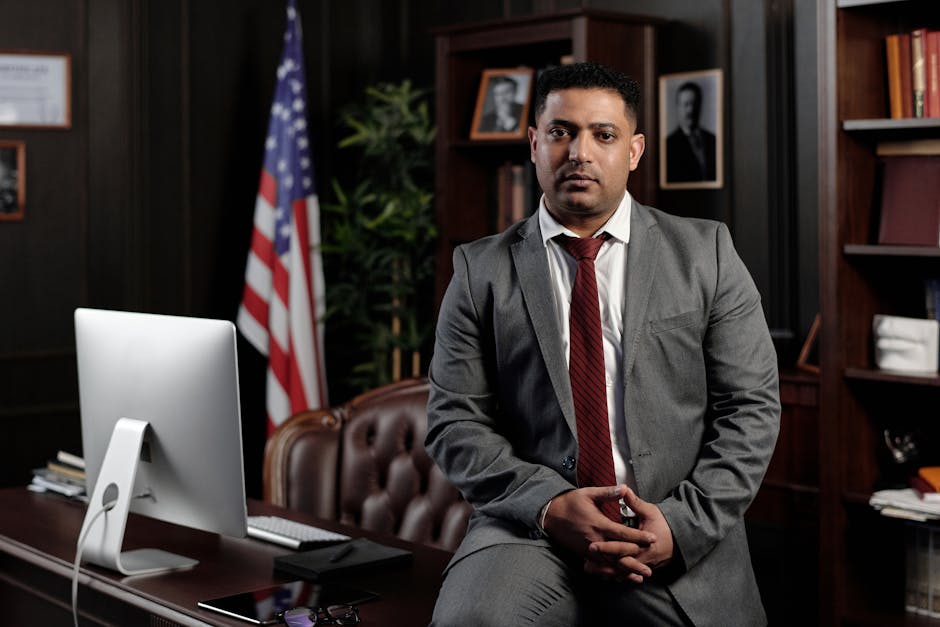 Attorney Funding - A professional attorney in  New York in a suit sitting in an office setting, with the American flag in the background.